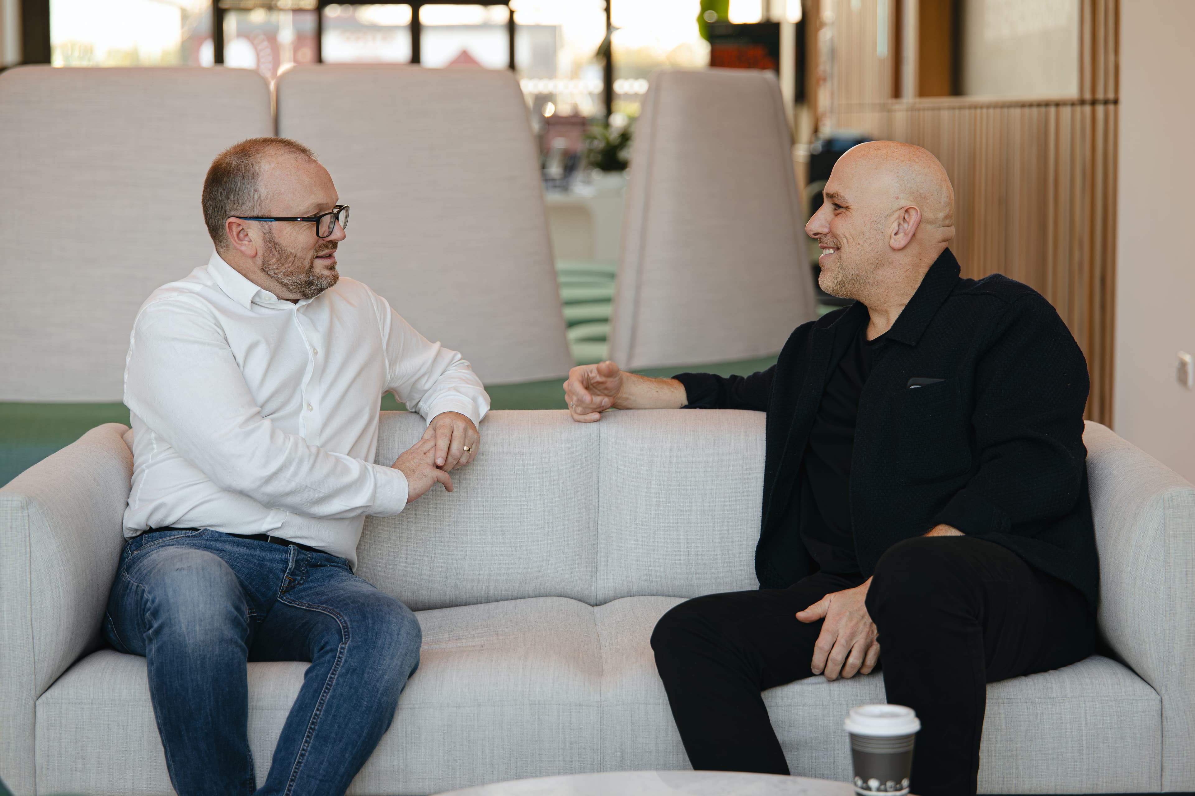 Two members of the Cyber Trust team talking on a sofa